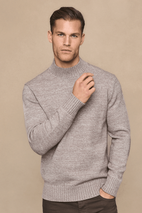 Man wearing a light brown sweater against a beige background